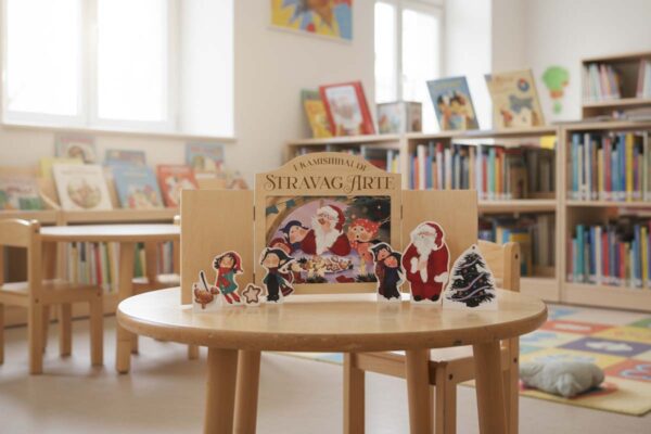 Babbo Natale e il biscotto dell'amicizia - storia kamishibai bilingue di StravagArte con burattini da ritagliare e flashcards - testo italiano e inglese - qr code per materiali didattici extra - teatrino kamishibai sul tavolo di una biblioteca per bambini